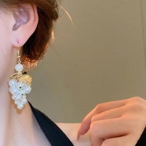 Detailed close-up of leaf and pearl grape cluster earrings on model for elegant style