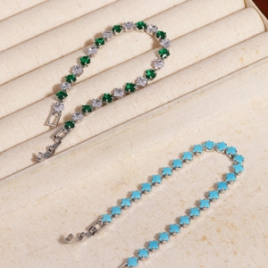 Detail of silver bracelets with green, white, and sky blue zircon gemstones in a jewelry box