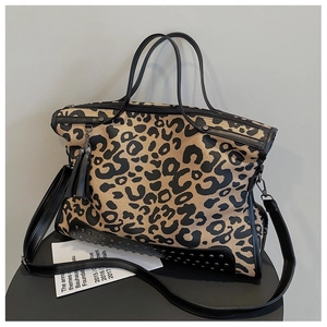 Close-up of leopard print tote bag with black metal rivets and fringe tassel detail