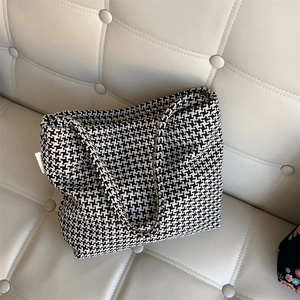 Detail shot of black and white houndstooth woven tote bag on white leather sofa