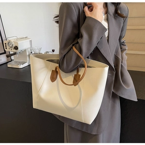Classic cream tote bag with brown leather straps shown on a model in a business setting