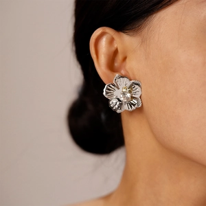 Gros plan de boucles d'oreilles fleur argentée avec cristal portées par un mannequin