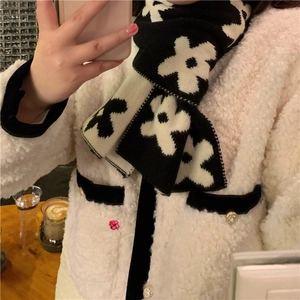 Detailed knit texture of a thick black and white floral scarf with soft fleece coat
