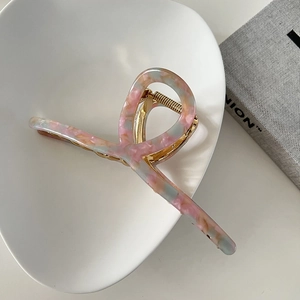 Detail of 13cm marble pink acetate hair claw with elegant golden metal twist design