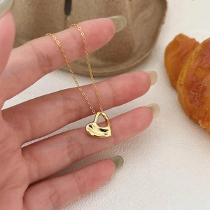 Elegant 925 sterling silver gold heart pendant necklace held in hand with cozy props