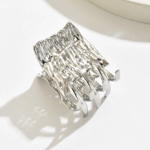Macro shot of silver textured metal hair claw with wavy ridges and polished finish