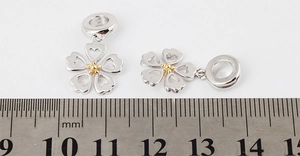 Silver cherry blossom pendant with gold stamen measured by a scale for jewelry DIY