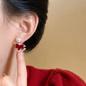 Detail of a red flocked horse earring with a white pearl and sparkling rhinestones