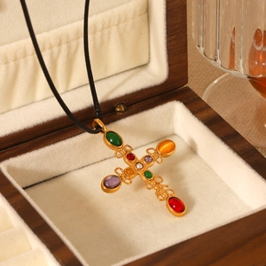 Detail of vintage gold cross pendant with colorful gemstones in a wooden jewelry box
