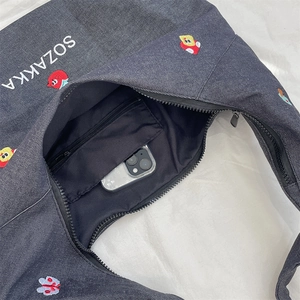 Internal view of denim tote bag showing zipper pocket and phone for capacity reference