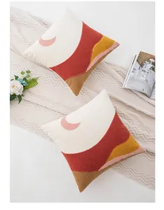Detail of two velvet square pillow covers with embroidered sun and mountain patterns