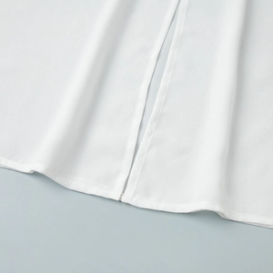 Detailed view of white chiffon shirt hem featuring precise side slit and fine stitching