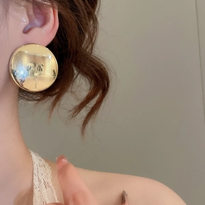 Vue latérale d'un mannequin portant une grande boucle d'oreille créole dorée et polie