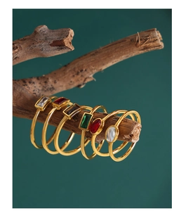 Detail of vintage gold rings with colorful gemstones on a natural wood branch
