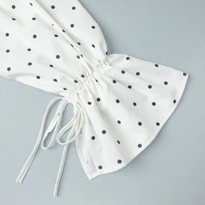 Detail of white polka dot flared sleeves with drawstring ties and ruffled cuffs