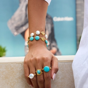 Detail view of double-layer turquoise and pearl bracelet with matching gold-tone rings