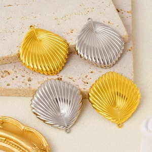 Detailed view of gold and silver stainless steel seashell pendants on a textured stone base