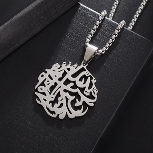 Macro view of a silver stainless steel Tree of Life pendant with Arabic calligraphy on box chain