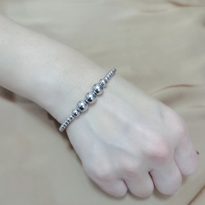 Close-up of silver beaded elastic bracelet with polished stainless steel beads on wrist