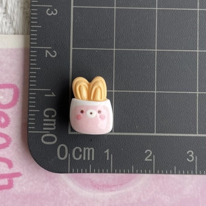 Macro shot of pink bunny bread resin charm on ruler showing 1.5cm size detail