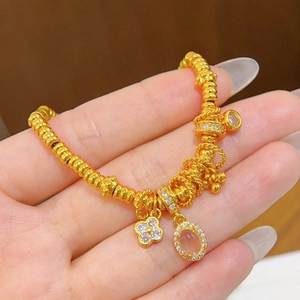 Detailed shot of a 24k gold bead bracelet with clover and oval gemstone charms