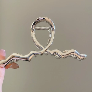 Detailed close-up of a silver wavy metal hair claw clip with a glossy mirror finish