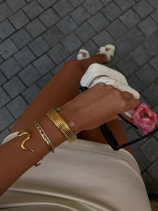 Detailed view of snake-shaped gold bracelet set with floral charms and ribbed bangles
