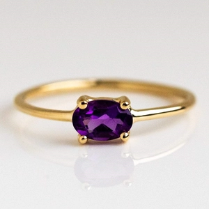 Close-up of gold plated brass ring with oval purple zircon in four-prong setting