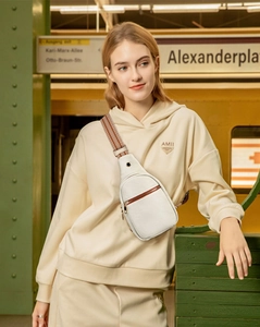 White leather crossbody sling bag with multi-zippers and wide fabric strap on a model