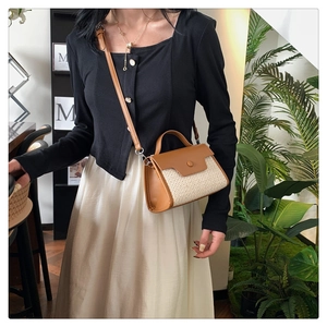 Sac bandoulière en cuir marron et paille porté par un mannequin dans un décor intérieur