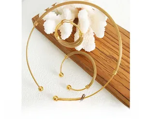 Detail of gold jewelry set with woven texture including collar, cuff, and hoop earrings