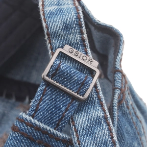 Macro detail of washed denim newsboy cap with metal buckle and GSIOR engraving