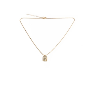Macro detail of gold plated square evil eye pendant with sparkling crystals and tassel