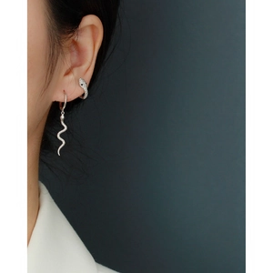 Close-up of a silver snake-shaped earring worn by a model against a grey backdrop
