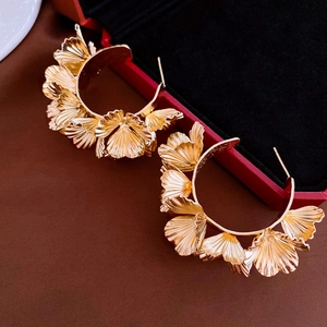 Vue détaillée de boucles d'oreilles dorées en feuilles de ginkgo sur fond sombre