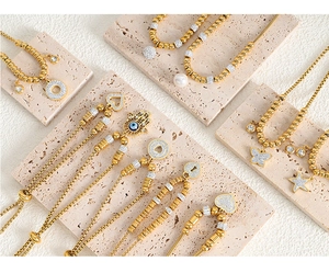 Detail of 18K gold-plated bracelets featuring Hamsa Hand and heart-shaped charms