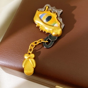 Macro detail of vintage surrealist eye brooch with rhinestones and gold drop pendant
