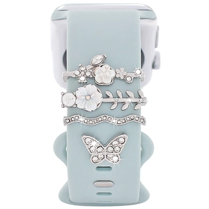 Close-up of decorative silver charms with butterfly and flowers on a blue watch strap