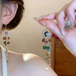 Close-up of bohemian tassel earrings with colorful glass beads and gold alloy hooks