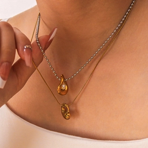 Two-tone layered necklace set with gold droplet pendant and pearl accent on model