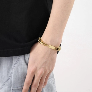 Gros plan d'un bracelet gourmette dorée avec plaque ID rectangulaire pour homme