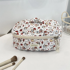 Detailed close-up of a white quilted cosmetic bag with cute cartoon cat and apple patterns