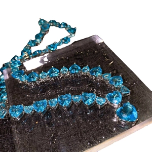 Sparkling silver necklace with heart-shaped blue topaz gemstones in a full diamond setting