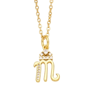 Macro shot of gold necklace featuring letter 'm' pendant with crown and micro-set zircons