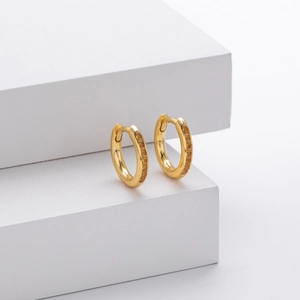 Macro shot of gold S925 sterling silver huggie earrings with inlaid yellow zircons