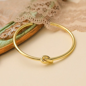 Eleganter minimalistischer Knoten-Armreif mit 18K Vergoldung auf Vintage-Spitzenhintergrund