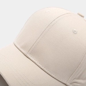 Detailed close-up of beige twill cotton baseball cap with ventilation hole and stitching