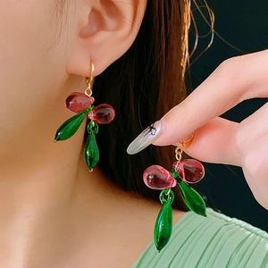 Vue détaillée de boucles d'oreilles cerises en verre rouge et vert portées par un mannequin