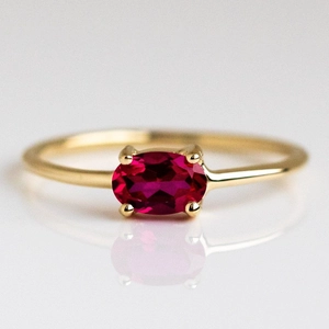 Macro shot of gold plated ring featuring a vibrant red oval zircon in a four-claw setting