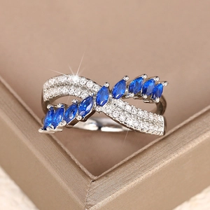 Close-up of marquise-cut blue stones and sparkling crystals on a criss-cross copper ring